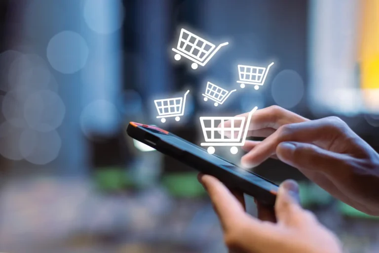 Hands using a smartphone with digital shopping cart icons floating above the screen.