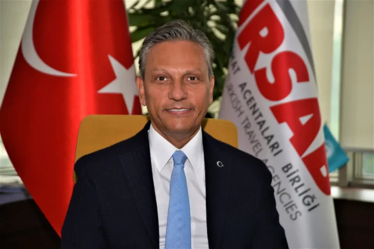 Portrait of Firus Baglikaya seated in front of a Turkish flag and a TÜRSAB flag.