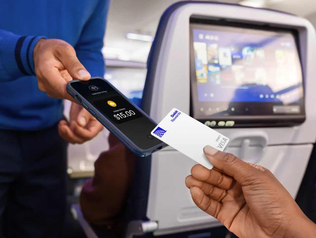 A passenger makes an in-flight payment using the United MileagePlus Debit Rewards Visa card.