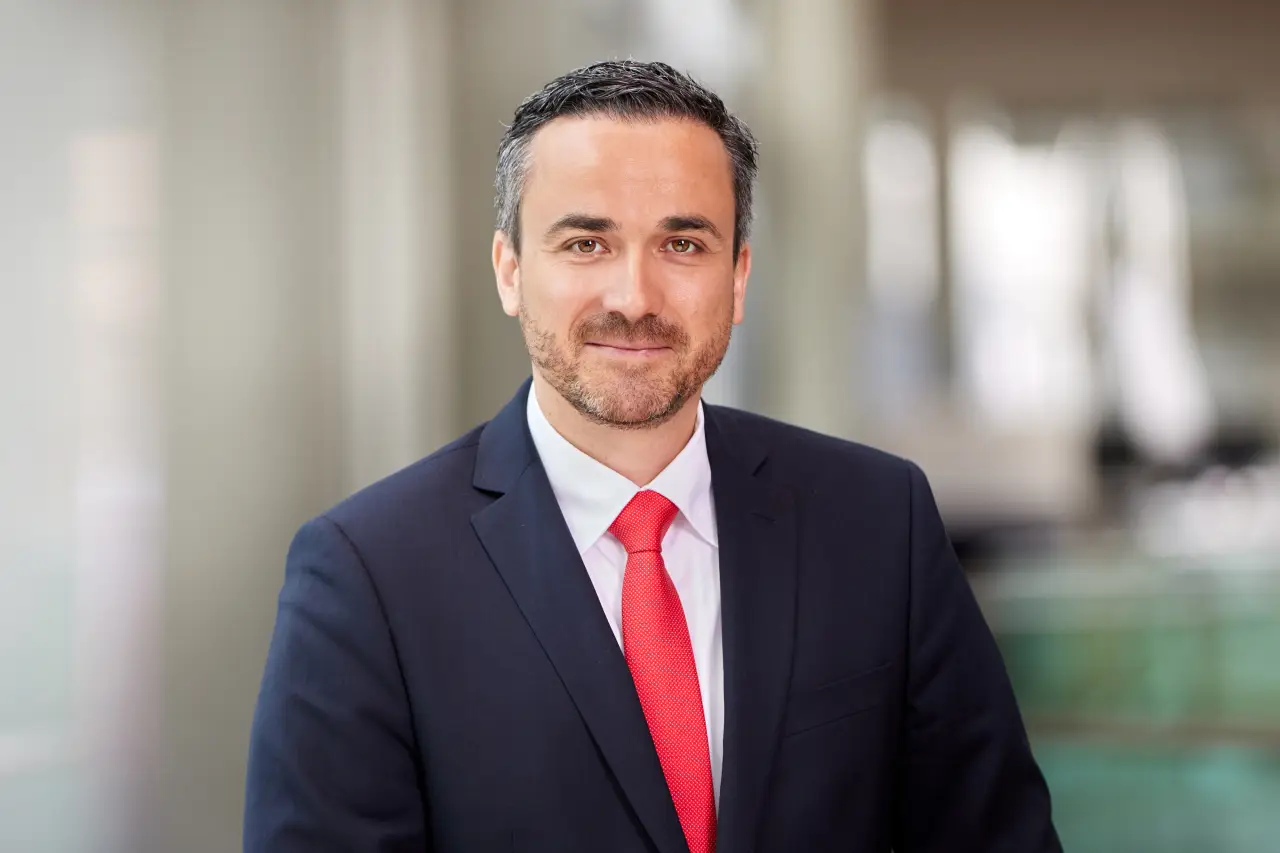 Marcus Schnabel, the airline executive in a dark suit and red tie standing indoors, facing the camera with a neutral expression.