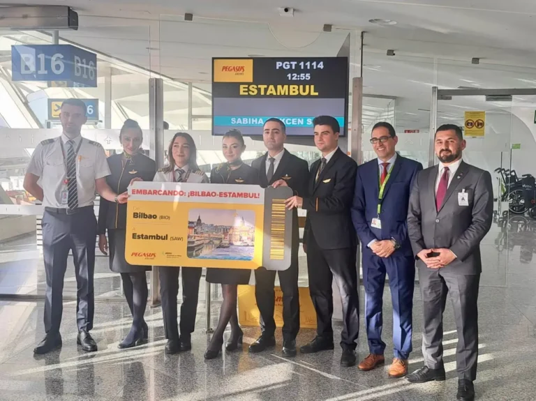 Pegasus Airlines crew and airport staff hold a large Bilbao–Istanbul boarding pass during the inaugural flight event at the airport gate.