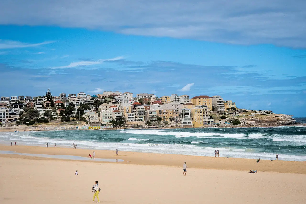 Wide view of Bondi Beach with sandy shoreline, waves, and coastal buildings in Sydney