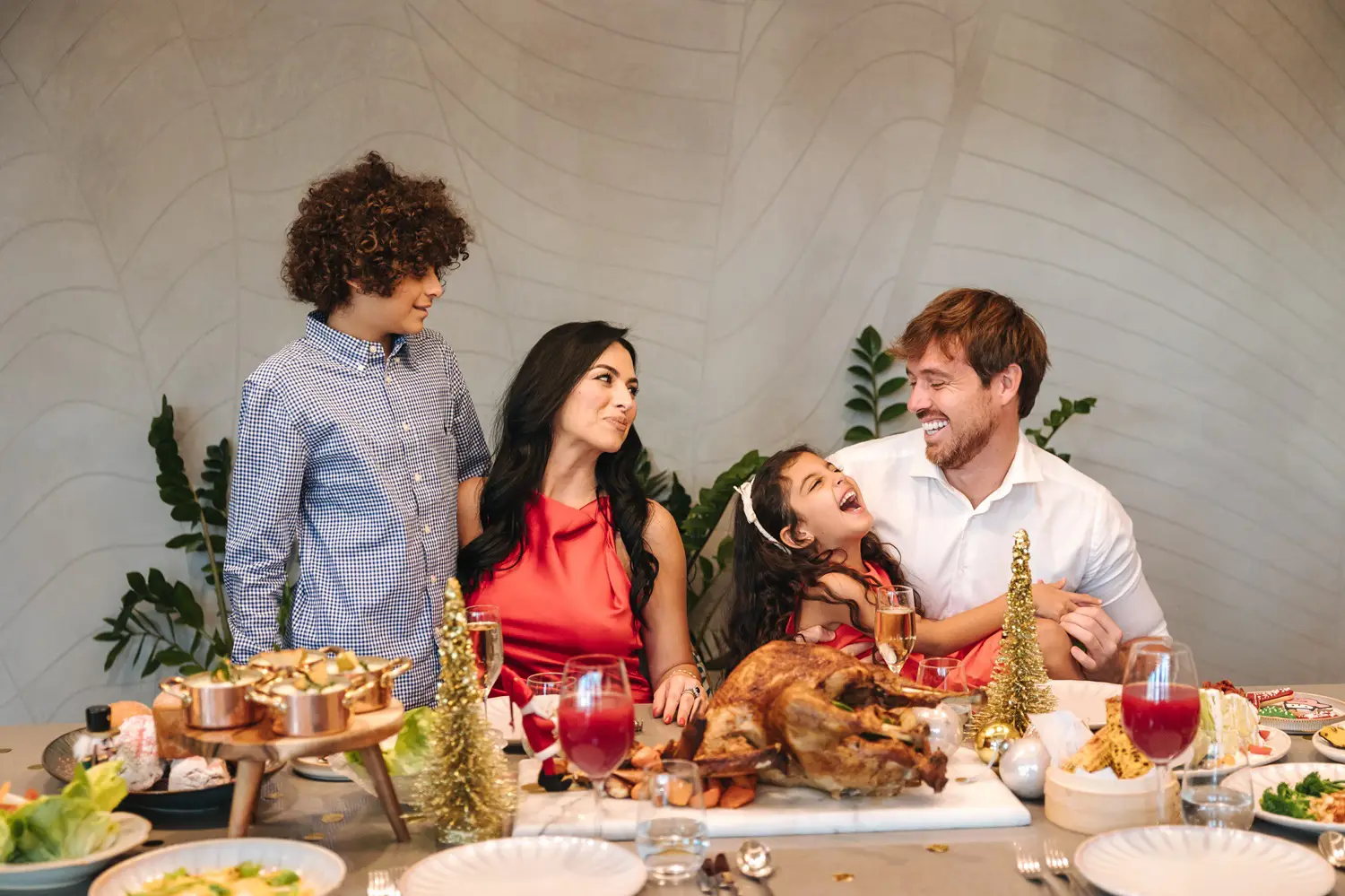 A family laughing together at a festive dinner table with roast turkey and holiday decorations.