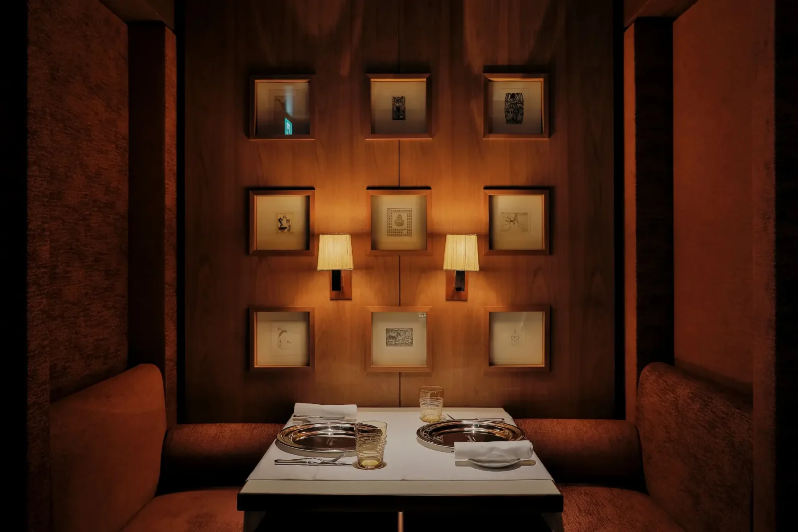 Intimate dining booth at Girandole by Alain Ducasse inside Park Hyatt Tokyo, featuring warm wood interiors and framed artwork.