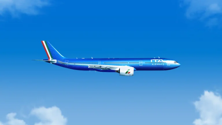 ITA Airways Airbus A330neo in blue livery flying against a clear sky with light clouds.