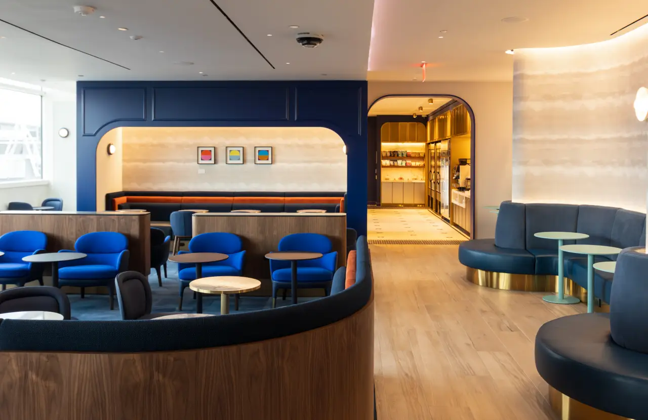 Interior of JetBlue’s BlueHouse lounge with modern seating, tables, and warm lighting at JFK Terminal 5