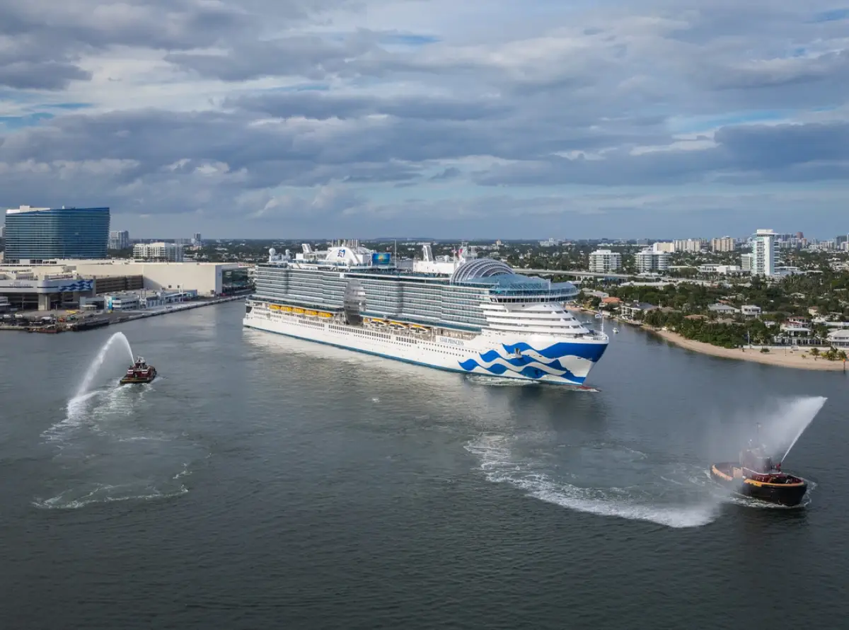 The Star Princess cruise ship departs Port Everglades escorted by two tugboats spraying water in celebration.