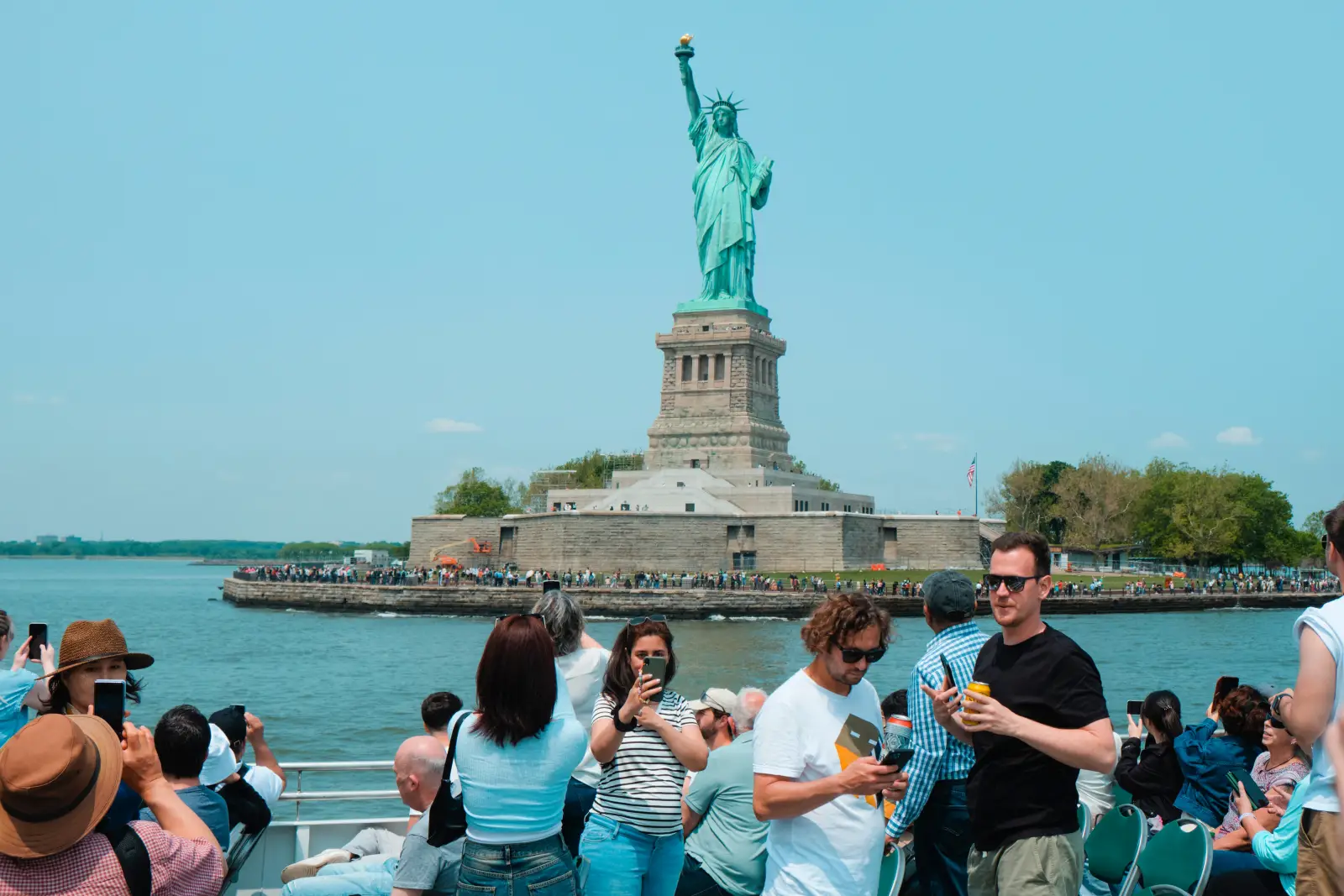 Tourists photograph the Statue of Liberty from a ferry in New York Harbor