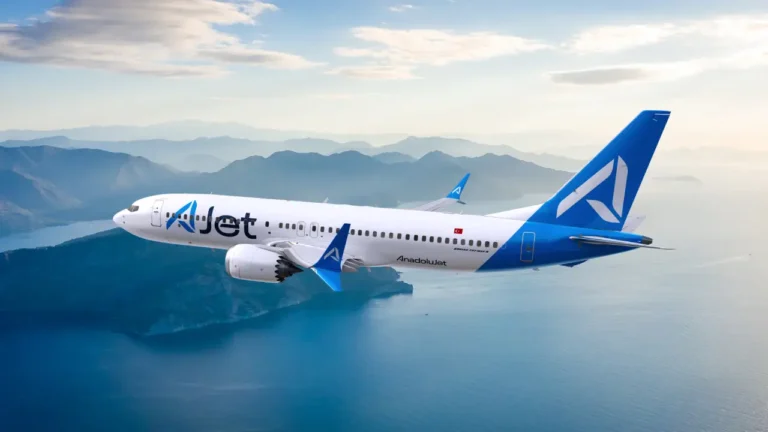 AJet Boeing 737-800 aircraft flying above a coastal mountain landscape under clear skies.