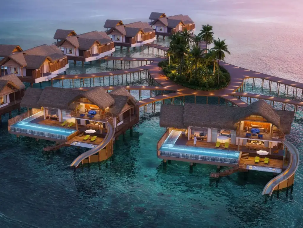 New Maldives Hotels &Amp; Resorts, 2025 &Amp; 2026 8 Aerial view of overwater villas with private infinity pools and water slides at DON MAAGA Maldives luxury resort at sunset.