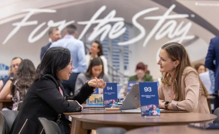 Business professionals networking and discussing at a Hilton event booth during a conference.
