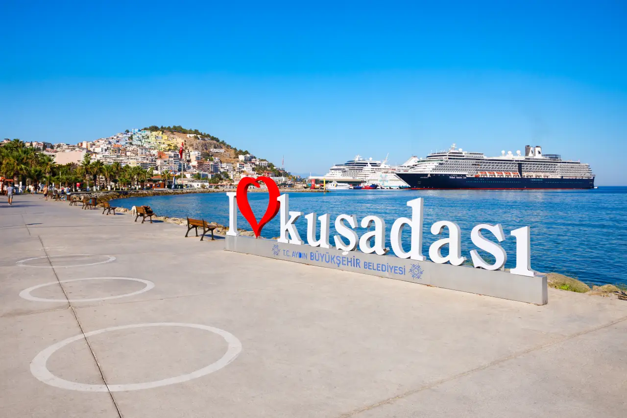 Kusadasi waterfront promenade with “I Love Kusadasi” sign and cruise ship docked in the harbor