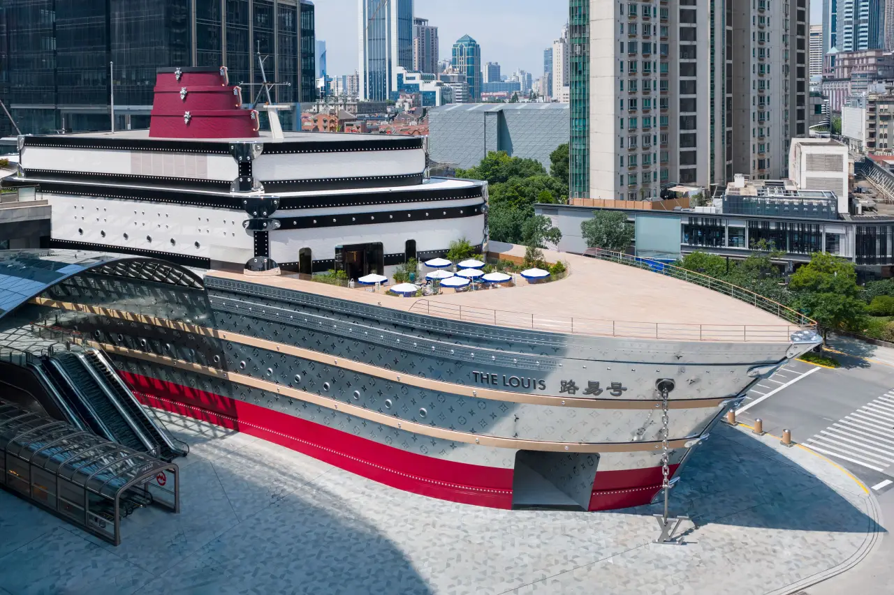 Life-size Louis Vuitton “The Louis” ship installation at HKRI Taikoo Hui on Nanjing West Road, Shanghai, with city skyline in daylight.