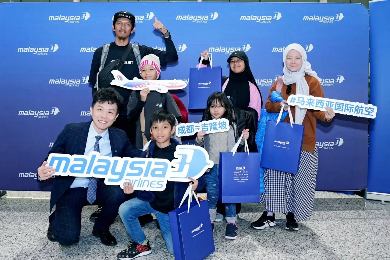 马来西亚航空恢复飞往大熊猫故乡成都的航班 4 乘客在成都航线启动照片墙上与马来西亚航空工作人员和品牌礼物合影。