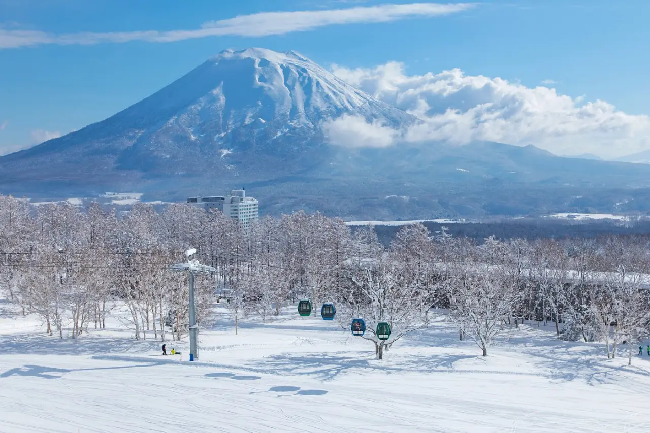 Hilton Debuts Tapestry Collection In Japan By Opening New Ski Resort In Niseko 3 Snow-covered ski slopes with gondola cabins and Mount Niseko Annupuri rising in the background under clear blue skies.