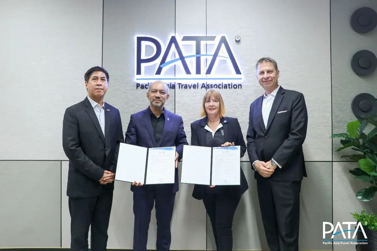 Pata And Phuket Hotels Association Sign Deal To Support Responsible Tourism 4 Four business professionals hold signed documents during a partnership signing at PATA headquarters, with the PATA logo displayed behind them.