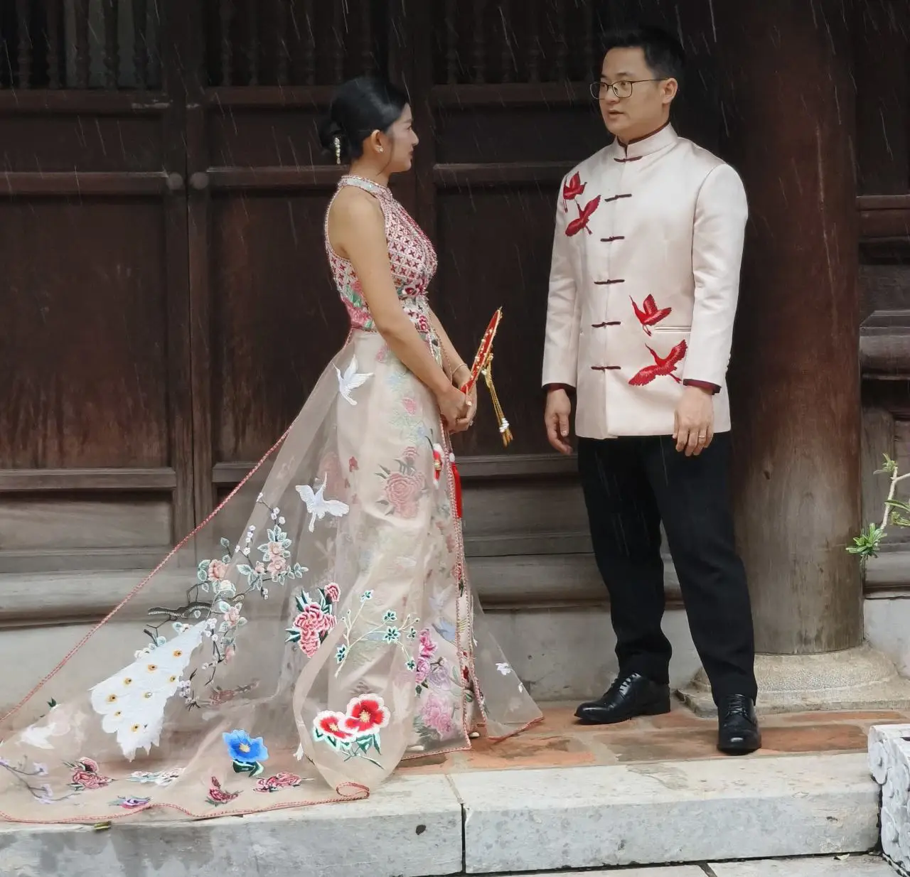 Temple Of Literature In Hanoi Showcases Vietnam’s Ode To Academic Excellence 11 A couple in traditional attire posing for wedding photos at the Temple of Literature in Hanoi, standing beneath a wooden pavilion during light rain.
