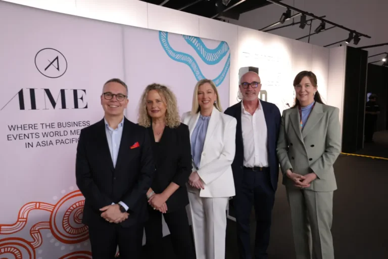 Group of five business leaders standing at the AIME 2026 press conference in front of the event branding backdrop in Melbourne.