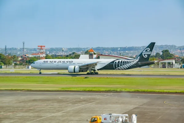 Air New Zealand wide-body aircraft taxiing on the runway at an international airport under clear skies
