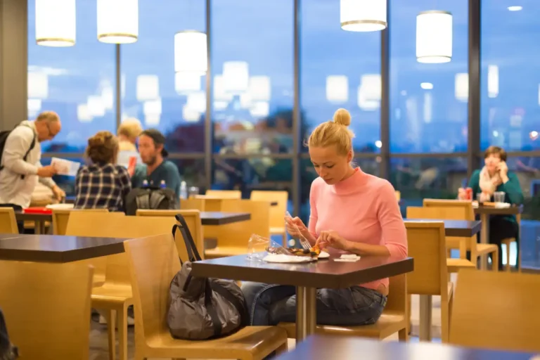 Young female traveler eating pizza at an airport restaurant while waiting for a late night flight