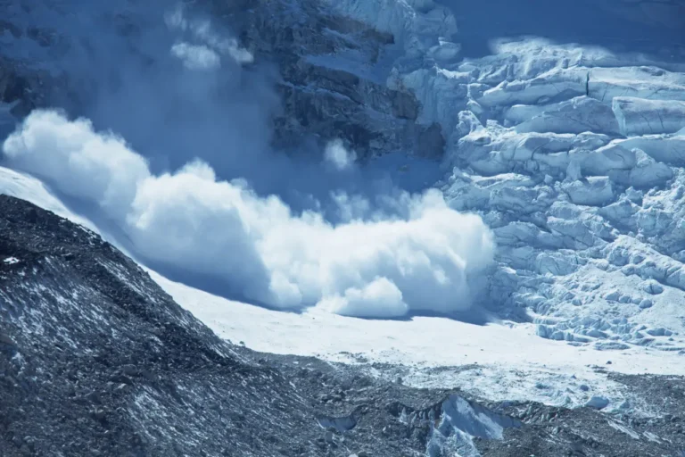 Snow avalanche rushing down a steep glacier-covered mountain slope in the Swiss Alps