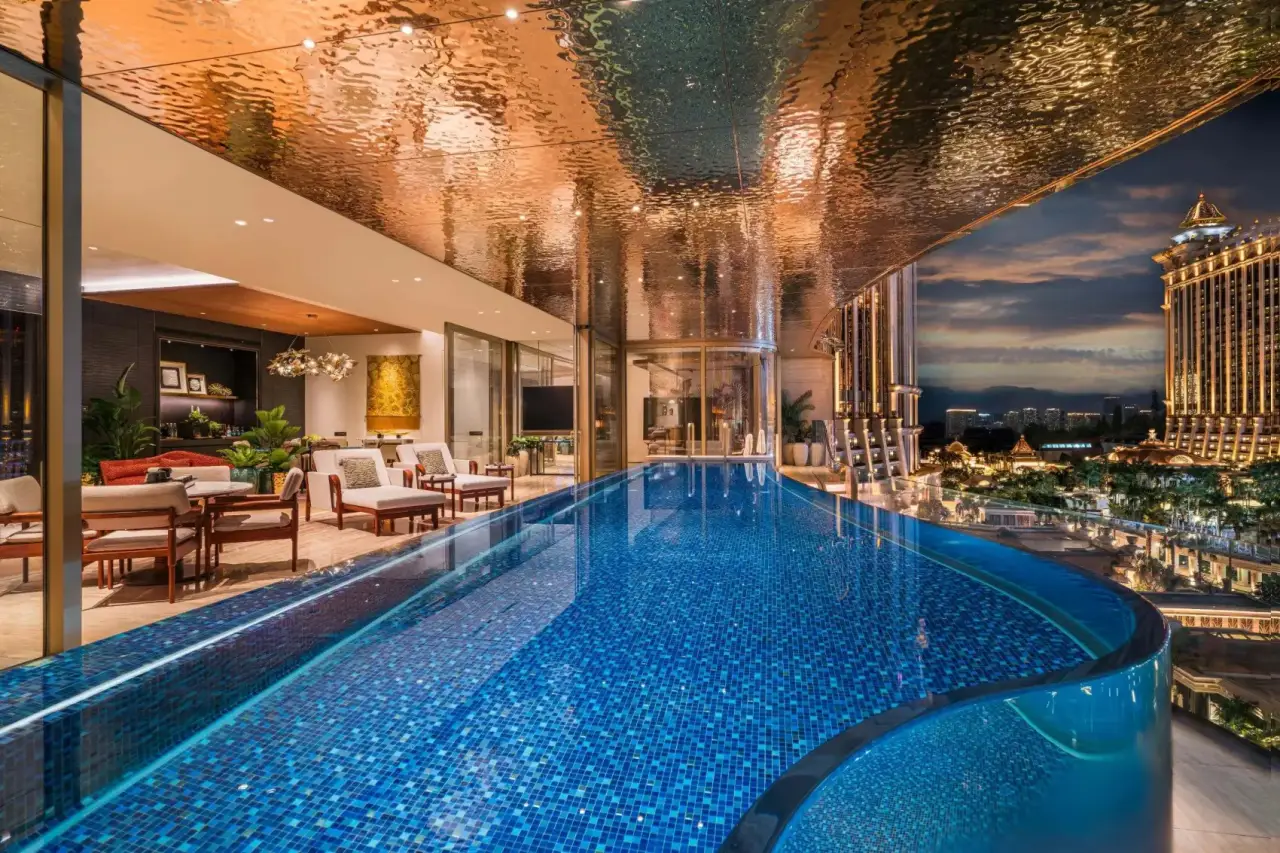 Private infinity pool terrace inside a Capella at Galaxy Macau penthouse overlooking the illuminated Macau skyline at night