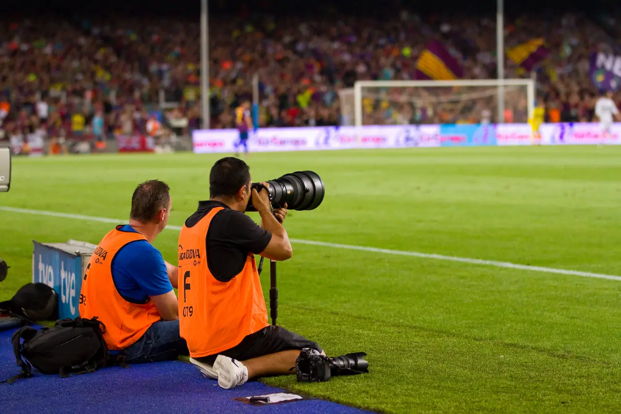 Photographers on the sideline capture action during a crowded football final at Camp Nou stadium in Barcelona.