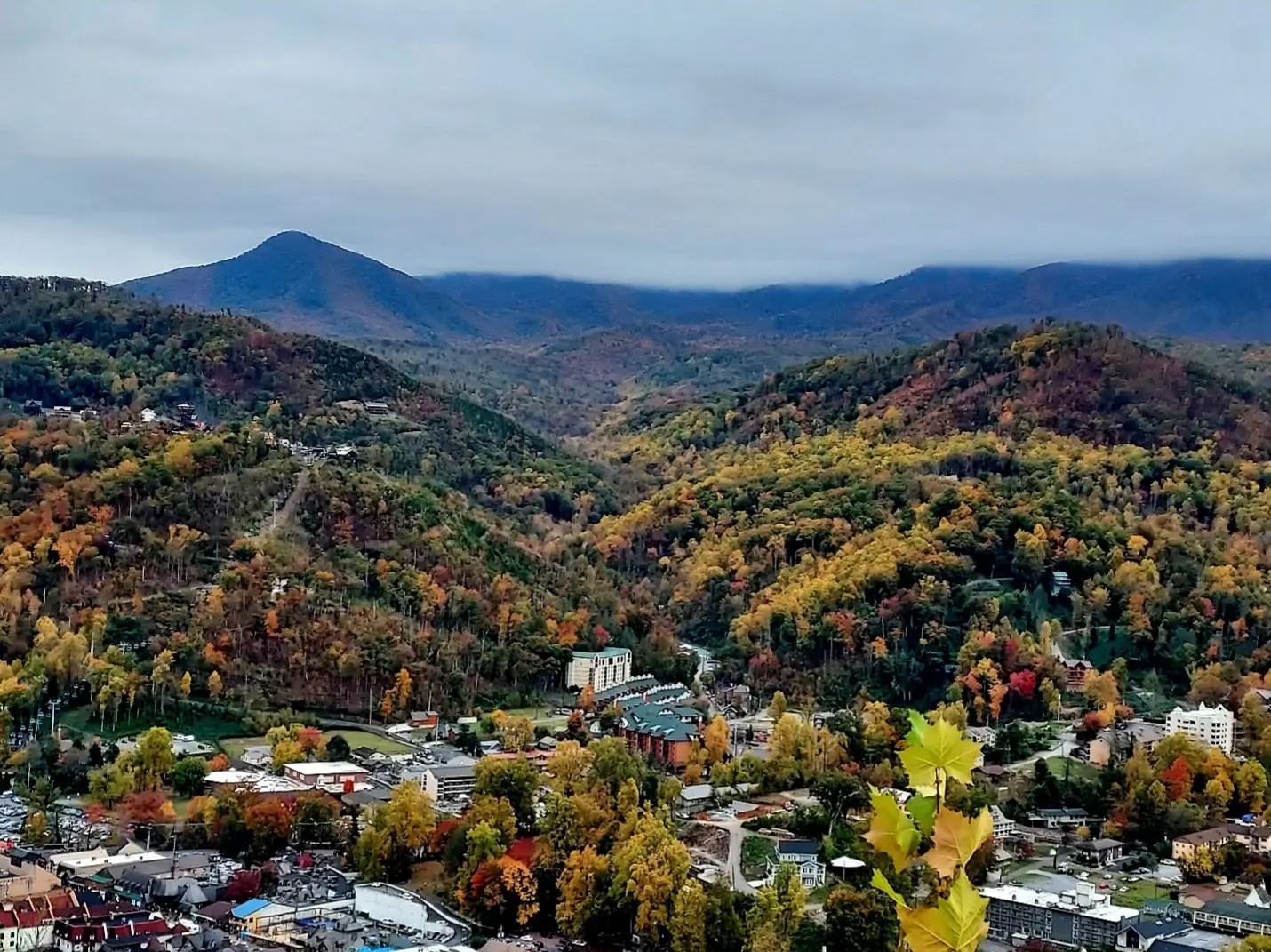 Autumn view of Gatlinburg, Tennessee, with colorful fall foliage covering the Smoky Mountains and the town nestled in the valley below.