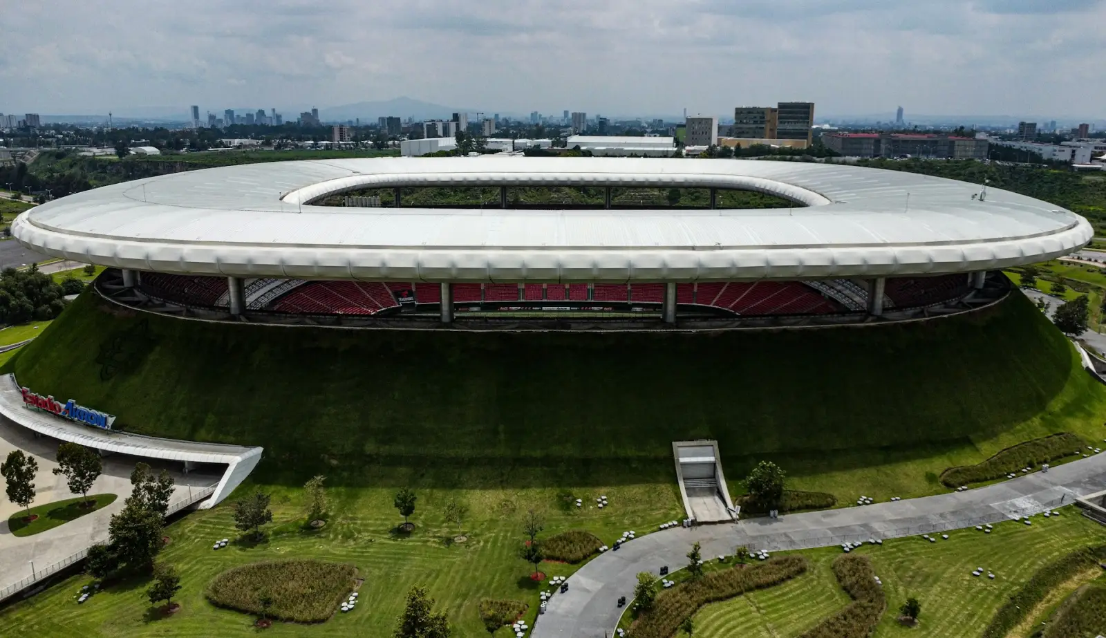 Aerial view of Guadalajara Stadium with its oval roof and green landscaped surroundings in Mexico