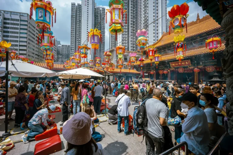Tourists and locals gather outside Wong Tai Sin Temple in Hong Kong decorated with colorful lanterns for Chinese New Year