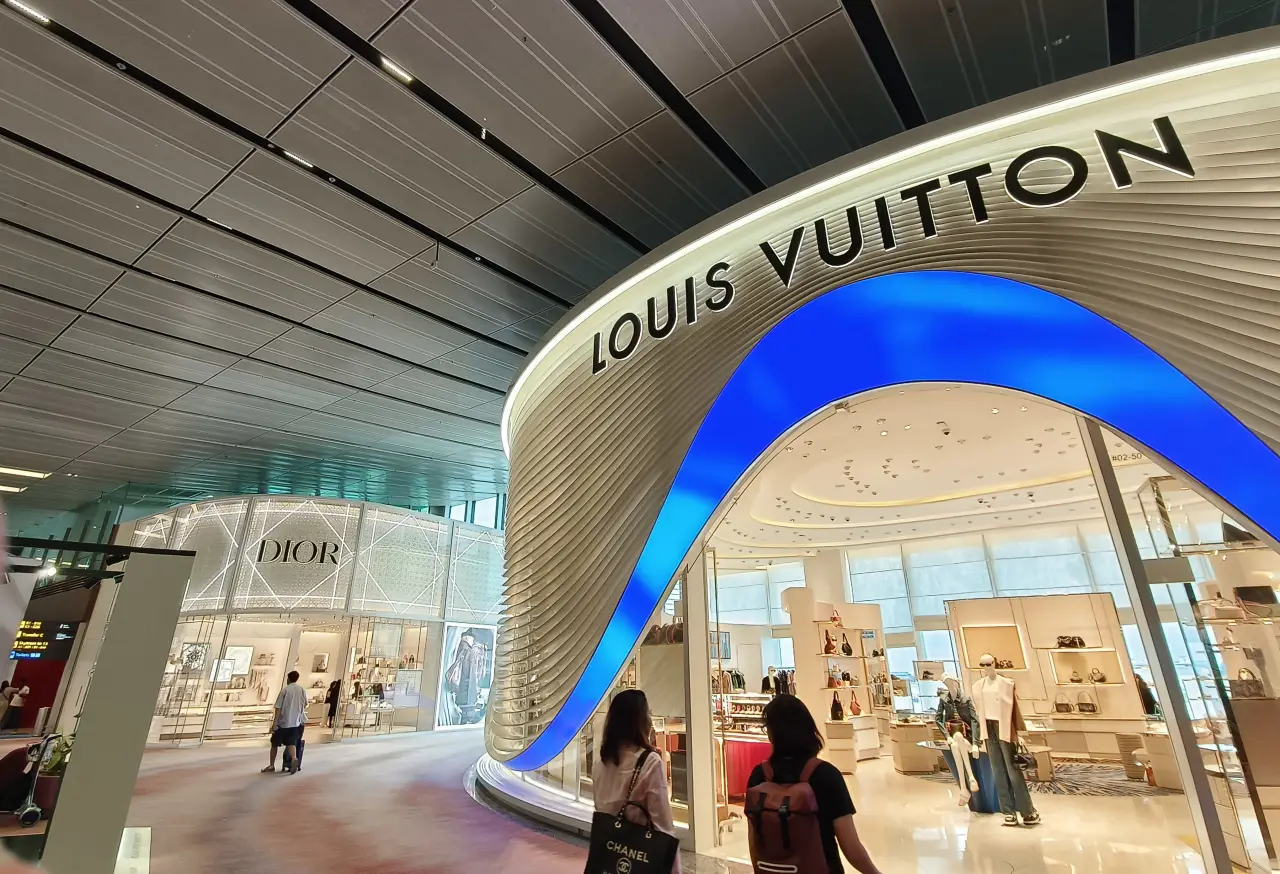 Luxury duty-free boutiques at Changi Airport featuring a Louis Vuitton store with a Dior boutique visible in the background