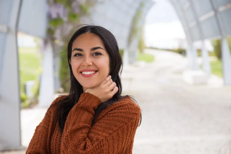 Smiling Mexican woman in autumn sweater standing under modern archway