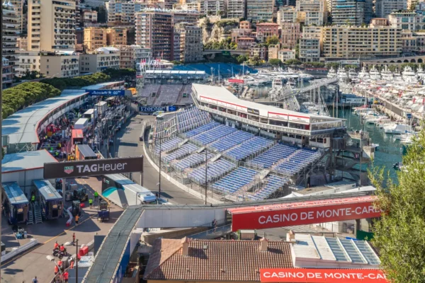 Grandstands overlooking Monaco harbor during a Formula 1 race weekend, with yachts, city skyline, and Monte Carlo streets below.