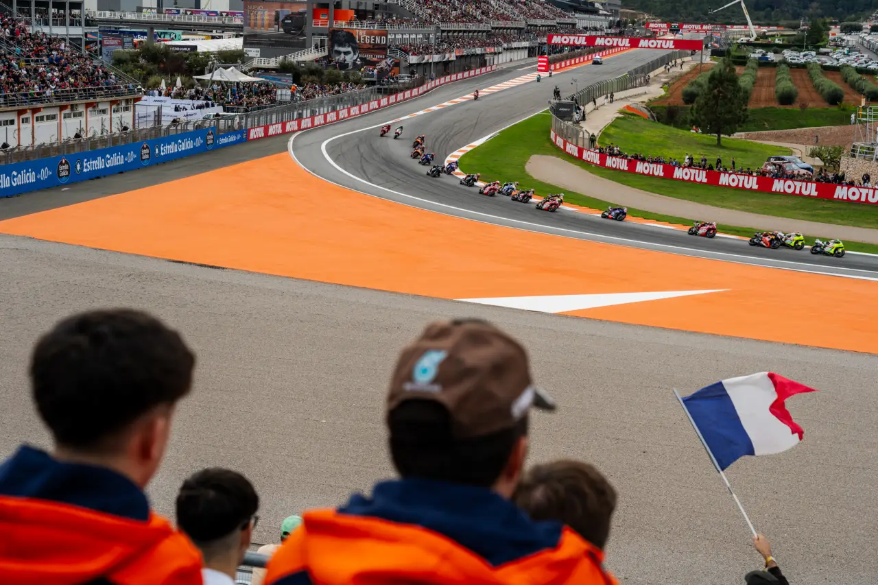 MotoGP riders race through a packed corner at Circuit Ricardo Tormo in Valencia as fans watch from the grandstands