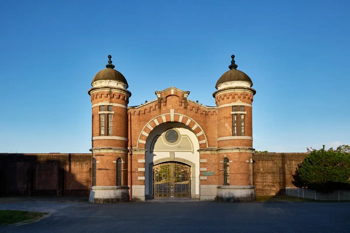 Japan’s First Luxury Hotel Housed In A Former Prison Will Open In June 7 Historic red brick entrance of Nara Prison Museum with twin towers and arched gateway in Japan