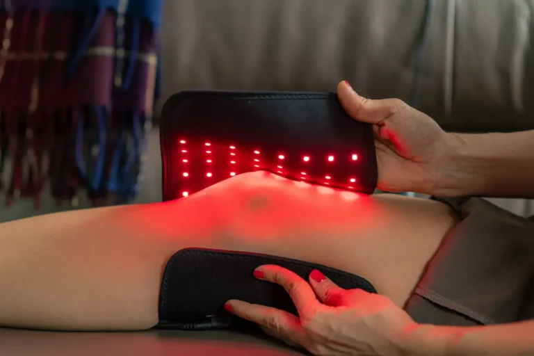 Portable red light therapy device being used on a person’s lower back for muscle recovery and pain relief.