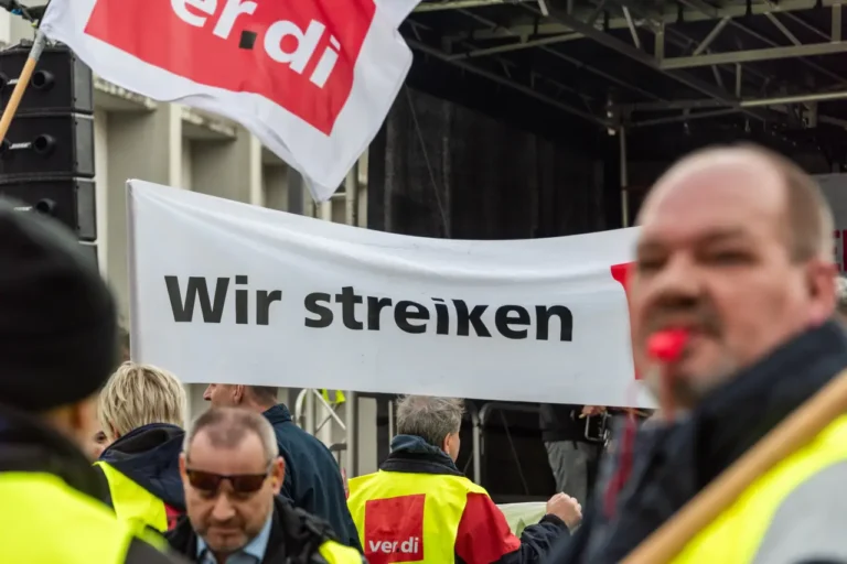 Public transport workers at a Verdi union strike in Germany holding a banner reading “Wir streiken” during a protest rally