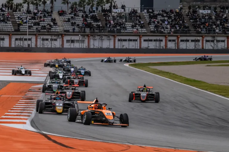 Sports Tourism 21 Formula 4 cars racing through a corner at Circuit Ricardo Tormo during the Winter Series in Valencia with packed grandstands.