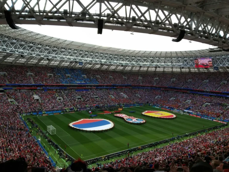Sports Tourism 20 Packed World Cup football stadium during opening ceremony with giant national flags displayed on the pitch before kickoff