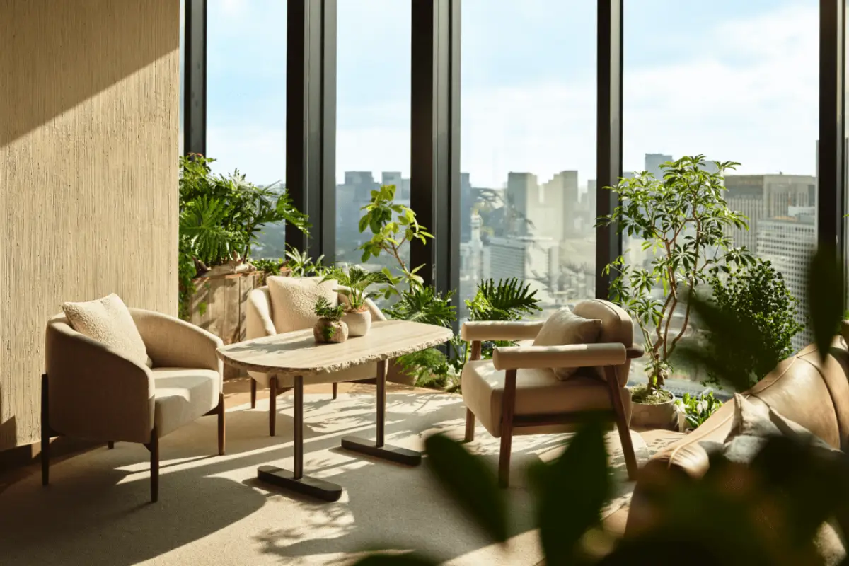 Nature-inspired hotel lounge at 1 Hotel Tokyo with indoor plants, natural materials, and panoramic city skyline views through floor-to-ceiling windows