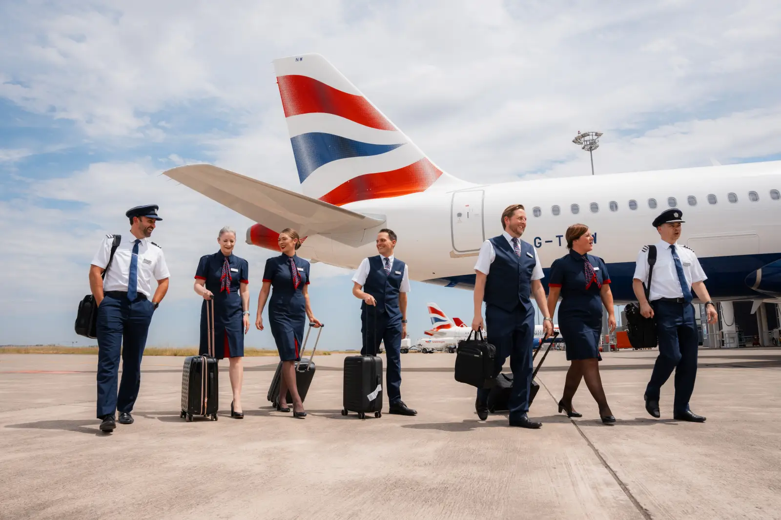British Airways cabin crew and pilots walking beside aircraft on airport runway