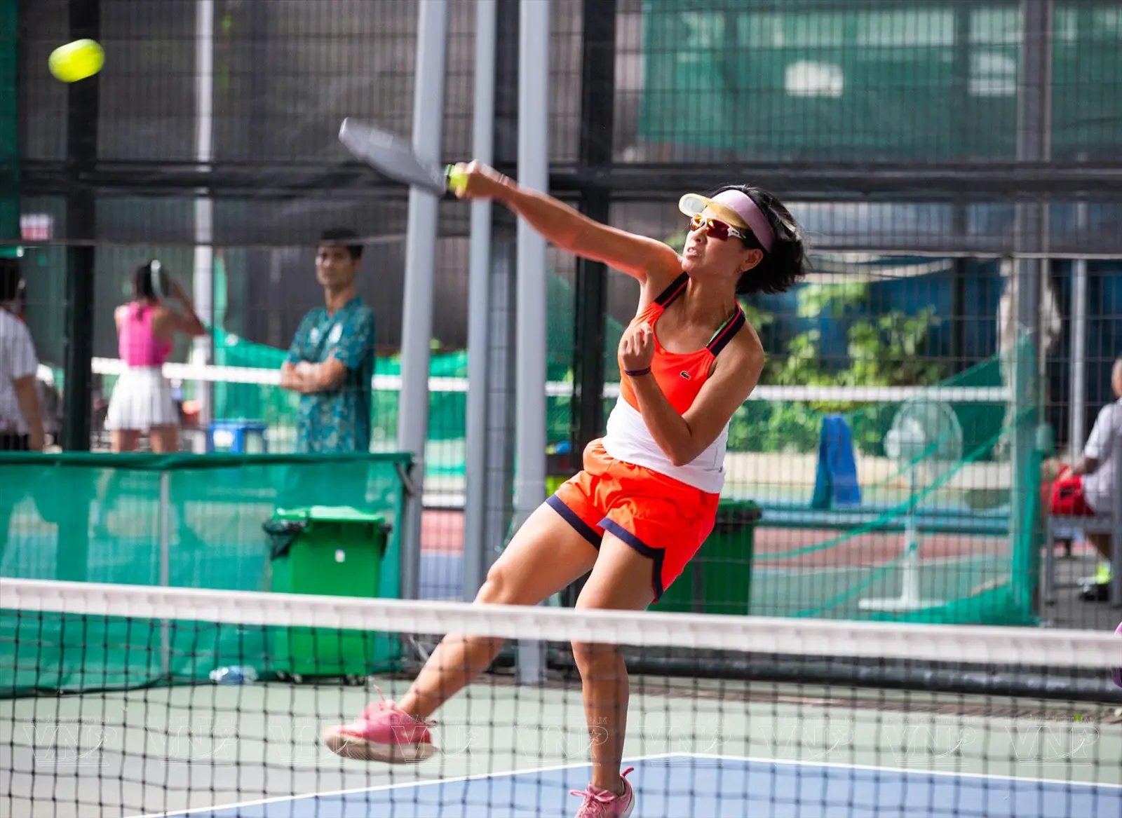 Female pickleball player in Vietnam hitting a shot during a match on an outdoor court