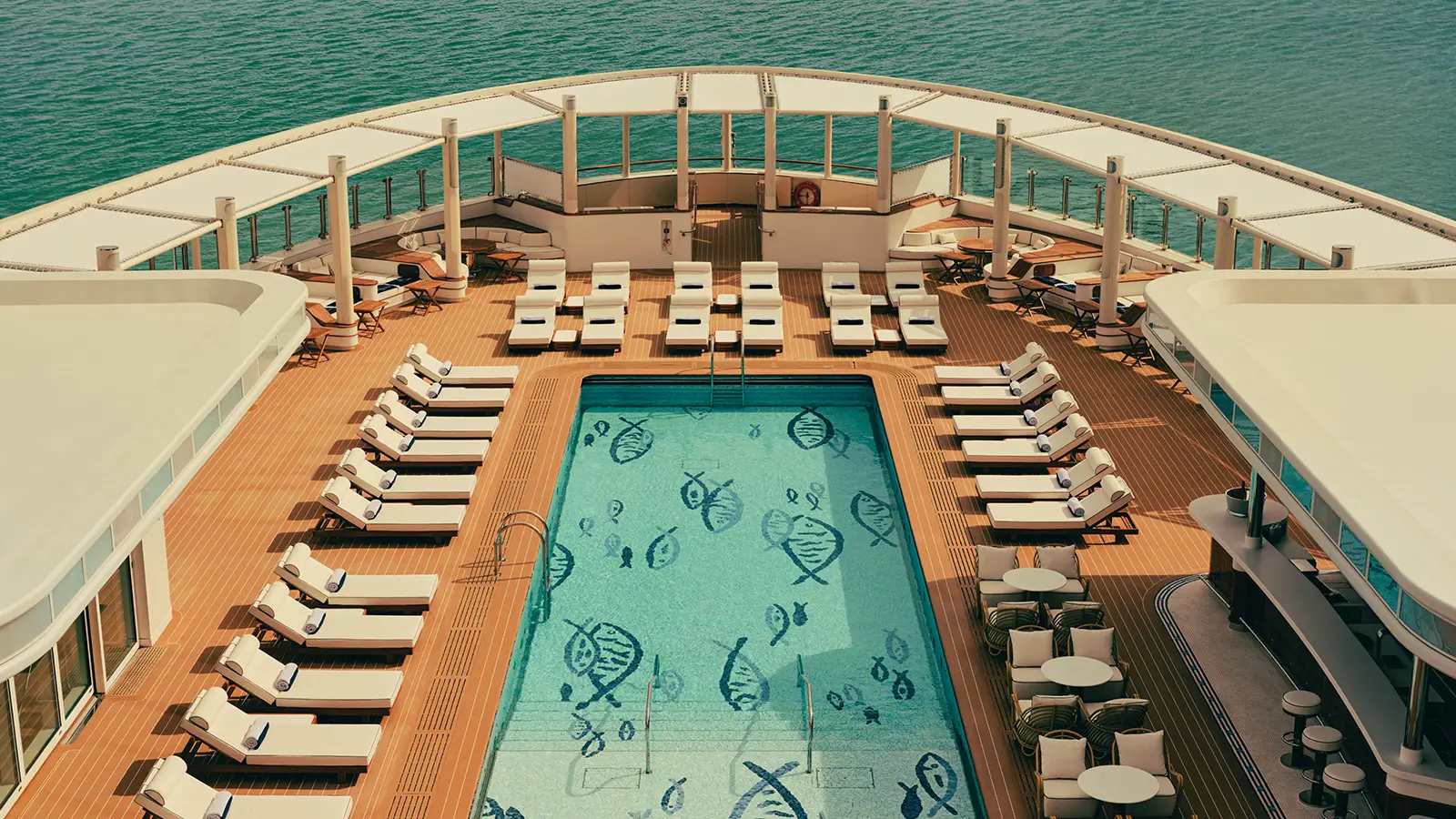 Luxury yacht pool deck with sun loungers, bar area and ocean views, showcasing Four Seasons yacht design