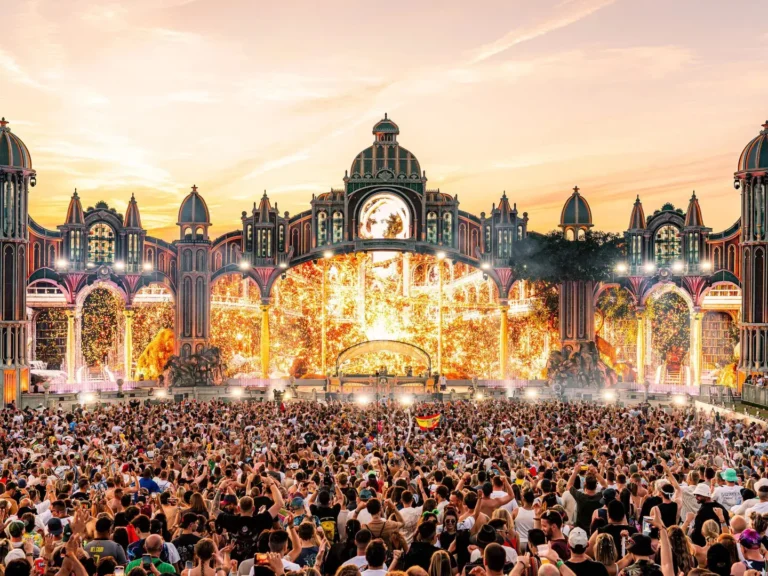 Massive crowd at Tomorrowland festival mainstage with fireworks and illuminated stage design