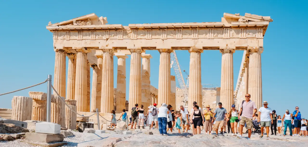 Tourists walking in front of the Parthenon temple on the Acropolis in Athens, Greece, on a sunny day