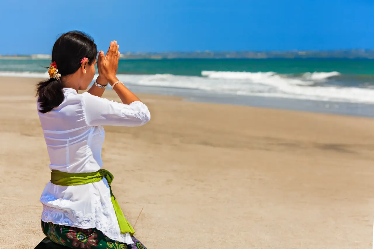 Balinese woman praying on beach during Nyepi ceremony in Bali