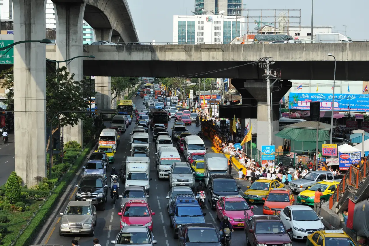 Heavy traffic congestion under elevated rail line in Bangkok as vehicles crowd a busy city street in Thailand during daytime