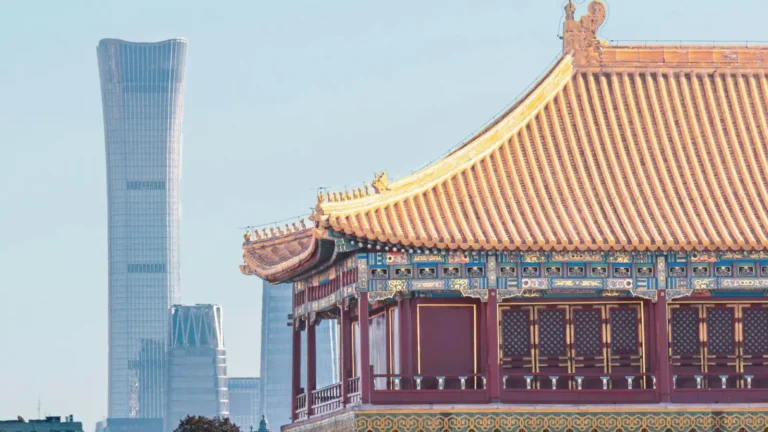 Traditional Chinese palace roof with modern Beijing skyline including skyscrapers in the background