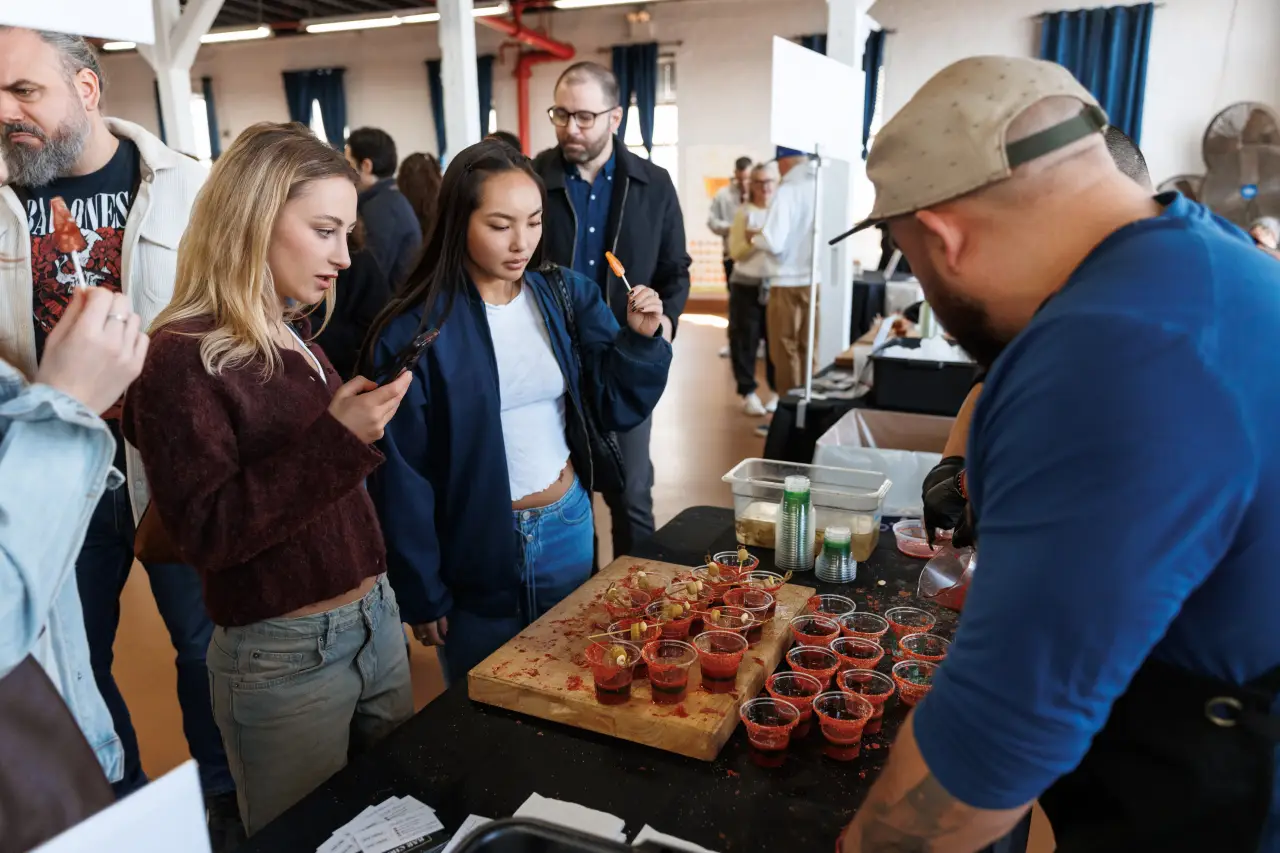 Nyc Bloody Mary Festival 2026 Reveals Best Cocktails And Mixes 3 Festival attendees sampling Bloody Mary cocktails at a tasting station during NYC Bloody Mary Festival in Brooklyn