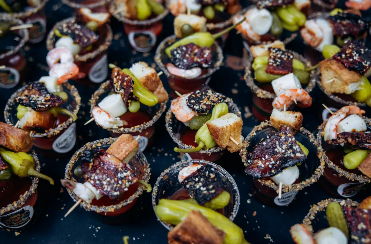 Assorted Bloody Mary cocktails with elaborate garnishes including shrimp, pickles, bacon, and bread at NYC Bloody Mary Festival